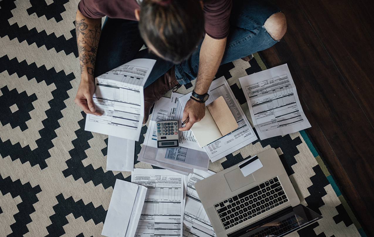 Man, sitting on floor, calculates bills